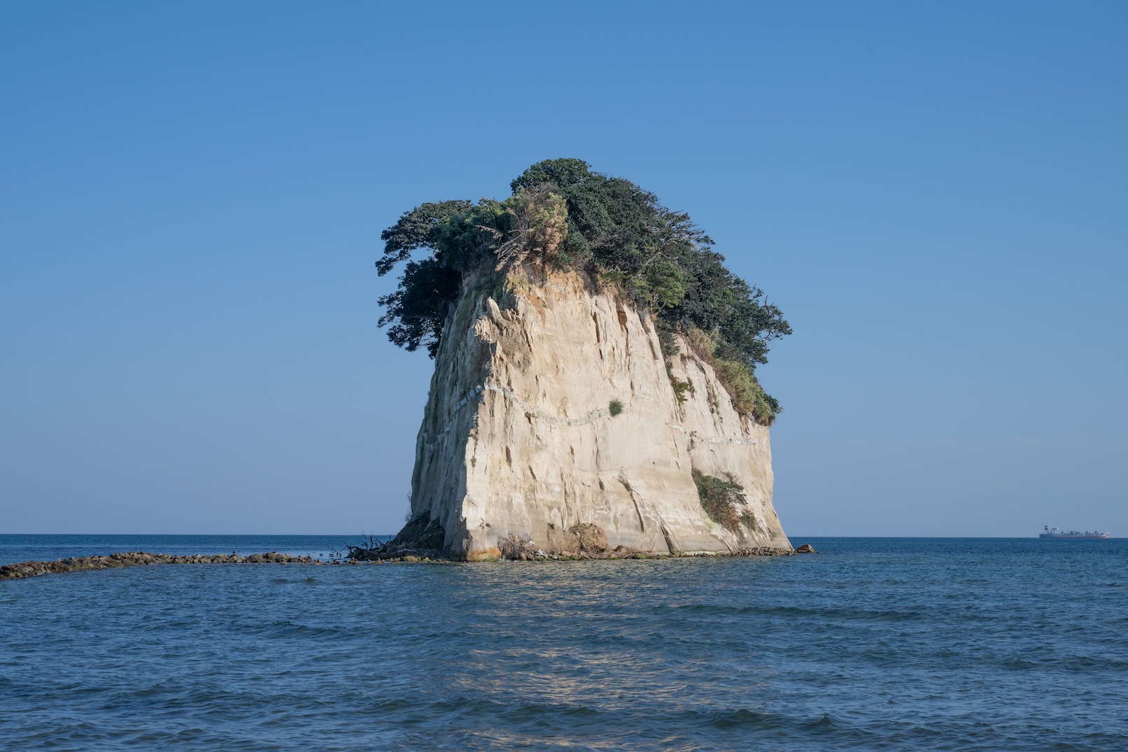 夕暮れに海へそびえる見附島の写真